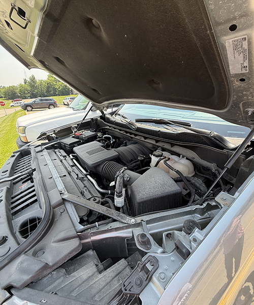 Image of truck hood open exposing engine which is slightly dirty.